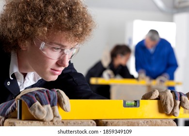 A close up shot of a young boy using a level tool in a bricklaying vocational school.
