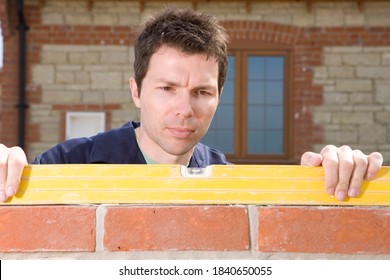 A Close Up Shot Of A Young Bricklayer Using A Level Tool On A Brick Wall.