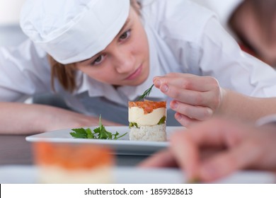 A close up shot of a young female trainee chef looking at desert while garnishing in a kitchen. - Powered by Shutterstock