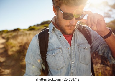 Close Up Shot Of Young Man On Country Hike. Caucasian Male Model Hiking Wearing Sunglasses With Sun Flare.