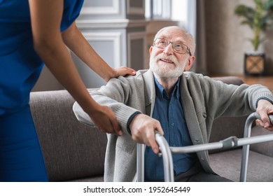 Close up shot of a young nurse helping disabled senior man with standing using walker. Cropped shot of physiotherapist supporting disabled elderly old patient.