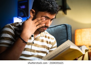 Close up shot young student with spectacles rubbing eyes due to eyes strain while reading book during late night - concept of feeling tired, early morning study and education - Shutterstock ID 2104331621