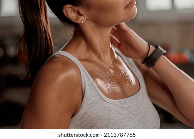 Close up of shoulders and neck fit female with sweat on skin after training, massaging neck muscles
