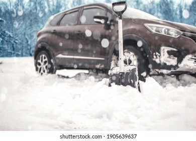 close up of shovel near car. auto blurred on background. transportation, winter, vehicle stuck in the snow. concept. 