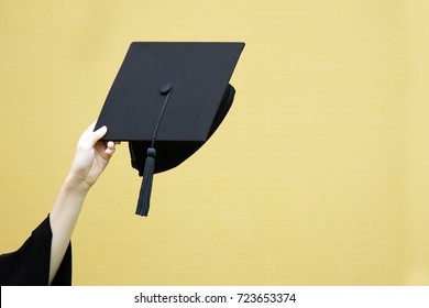 close up show hand hold hat in background yellow. Shot of graduation caps during commencement,Student Commencement University Degree Concept , Celebration Education Student Success Learning Concept.