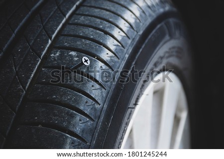 A close up shows a sharp metal screw puncture to automobile tire, Screws puncture into the side of the tire.
