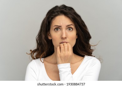 Close Up Of Shy Doubtful Girl Anxious About Problem. Studio Portrait Of Awkward Young Office Woman Biting Nails Feeling Embarrassed, Confused, Nervous, Looking At Camera, Isolated On Grey Background.