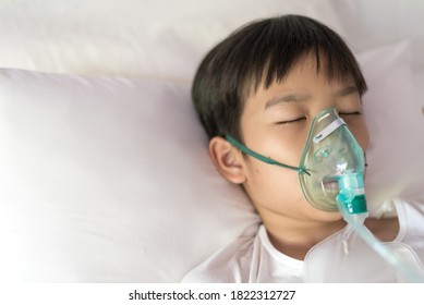 Close up sick Yong asian boy with face oxygen mask lay on a white bed at hospital. COVID 19 concept. - Shutterstock ID 1822312727