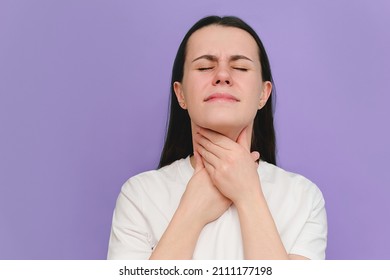 Close Up Of Sick Young Female Suffering From Sore Throat, Isolated On Purple Studio Wall. Causes Of Throat Pain Include Flu, Common Cold, Bacterial Infections, Pneumonia Or Allergies. Medical Concept