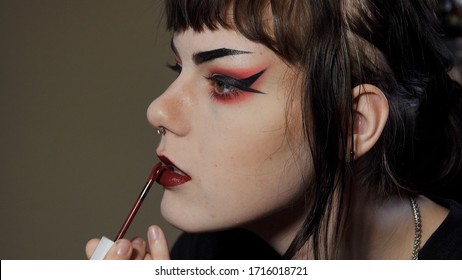 Close Up Side Angle Of A Goth / Punk Look Teen Girl Applying Dark Red Lipstick