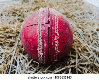 Close up of a side lit red cricket ball on the brown carpet or net background

