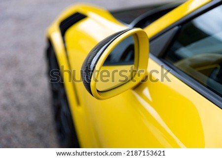 Close up of a side mirror of a yellow sports car