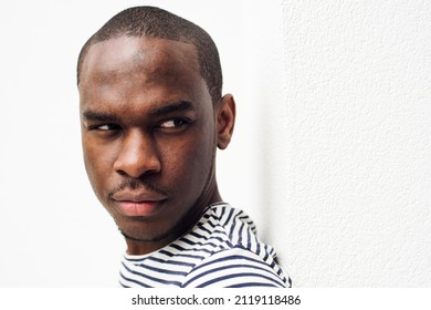 Close Up Side Portrait Serious African American Man Leaning Against White Wall And Glancing 