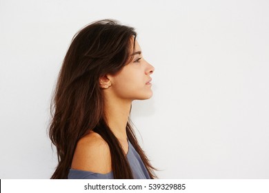 Close Up Side Portrait Of Young Female Standing Against While Wall