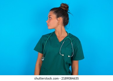 Close Up Side Profile Photo Beautiful Doctor Woman Wearing Medical Uniform Over Blue Background Not Smiling Attentive Listen Concentrated