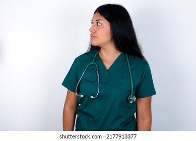 Close Up Side Profile Photo Doctor Hispanic Woman Wearing Surgeon Uniform Over White Background Not Smiling Attentive Listen Concentrated