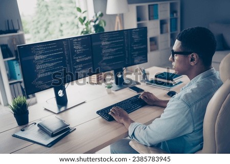 Close up side profile photo of professional young guy it specialist create code looking two modern monitors typing keyboard stay in office