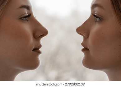 Close side profile view of two women facing one another with calm expressions, soft natural light, and a blurred neutral background that creates a clean