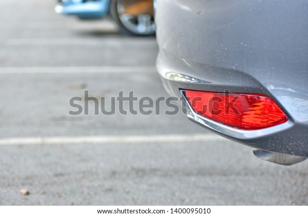 Close up side of rear fog lamp of a\
car parking in the indoor parking lot on blurred many\
cars.