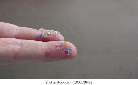 Close up side shot of microplastics on human fingers. Creative concept of water pollution and global warming. Climate change idea. Soft focus on a bunch of plastic rubbish that cannot be recycled.