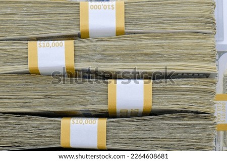 Close up side view of 4 straps of ten thousand one hundred US dollar bills stacked on top of each other