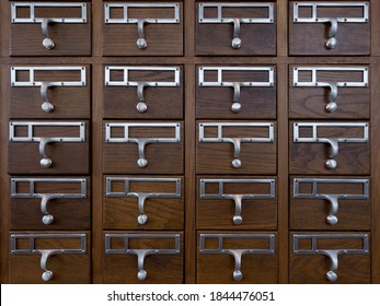 Close up side view of antique library drawers. Cabinet is made of oak wood with silver colored pulls and name plate holders.