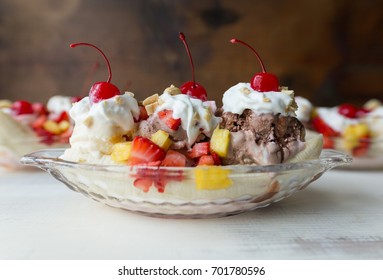 Close up side view of a banana split with whipped cream, peanuts and cherries.