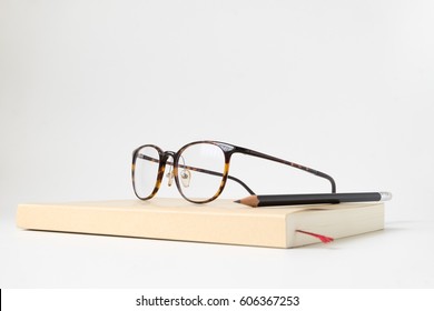 Close Up Side View Book With Pencil And Glasses On White Background