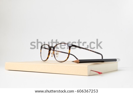 Close up side view book with pencil and glasses on white background