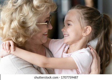 Close Up Side View Faces Of Loving Little Girl Hugs With Love Showing Sincere Strong Attachment To Old Grandma Looking At Each Other Feeling Affection Gratitude For Protection And Candid Bond Concept