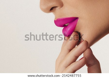 Close up side view of the lips of a beautiful woman with pink lipstick and perfect shiny skin. Cosmetology or fashion makeup concept. Filmed in a beauty studio. a passionate kiss. fuchsia color