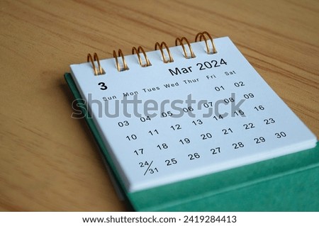 Close up side view of March 2024 calendar on wooden desk. Calendar concept.
