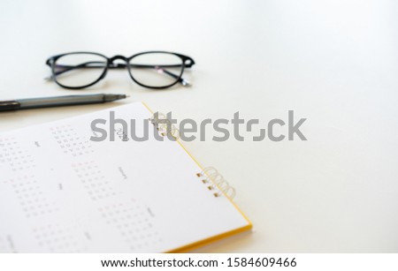 close up side view on  white calendar schedule background with eyeglasses and pen to make plan or manage timetable each day for planning work in new year 2020 resolution concept