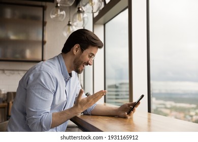 Close Up Side View Overjoyed Businessman Wearing Glasses Looking At Phone Screen, Chatting Online, Making Video Call, Excited Young Man Reading Unexpected Good News, Money Refund, Online Lottery Win