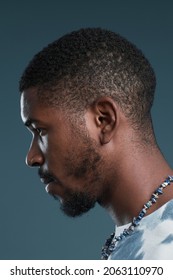 Close up side view portrait of handsome African-American man against blue, focus on profile outline