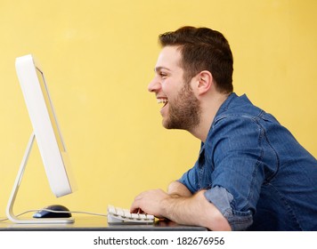 Close Up Side View Portrait Of A Happy Young Business Man Laughing And Looking At Computer Screen