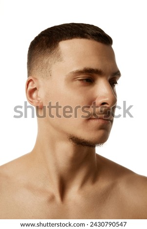 Close up side view portrait of young brunette man with short haircut and looking away against white studio background. Concept of beauty treatment, male health, body care, spa treatment, hygiene.