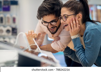 Close Up Side View Of Pretty Happy Excited Hipster Young Love Couple Testing New Smart Gadgets In A Tech Store.