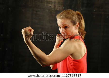 Similar – Close up front portrait of one young mid adult athletic woman in sportswear in gym over dark background, standing in boxing stance with hands and fists, looking at camera