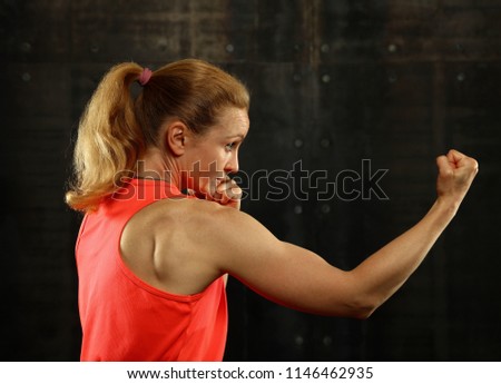 Similar – Close up front portrait of one young mid adult athletic woman in sportswear in gym over dark background, standing in boxing stance with hands and fists, looking at camera