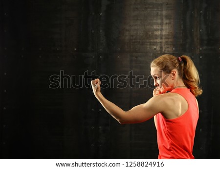 Similar – Close up front portrait of one young mid adult athletic woman in sportswear in gym over dark background, standing in boxing stance with hands and fists, looking at camera