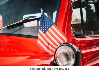 Close Side View Of Red Pickup Truck With Small American Flag Waving. Close Side View Of Red Pickup Truck American Flag Waving. 4th of July holiday. American flag blowing in the wind. Independence Day