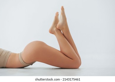 Close up side view. Woman in underwear with slim body type is posing in the studio.