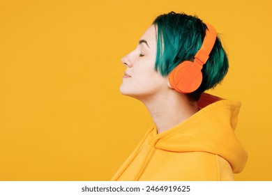 Close up side view young fun happy woman with dyed green hair wearing hoody casual clothes listen to music in headphones isolated on plain yellow orange background studio portrait. Lifestyle concept - Powered by Shutterstock