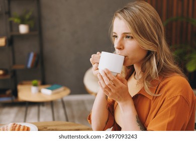 Close up side view young woman she wear orange shirt drink coffee sitting alone at table in coffee shop cafe relax rest in restaurant during free time indoors. Freelance mobile office business concept - Powered by Shutterstock