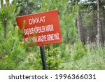 Close up of a sign in the forest in Metu, Ankara, Turkey to warn for dingos in Turkish. Beware of Dingos. Do Not Enter Alone. Be careful road sign.