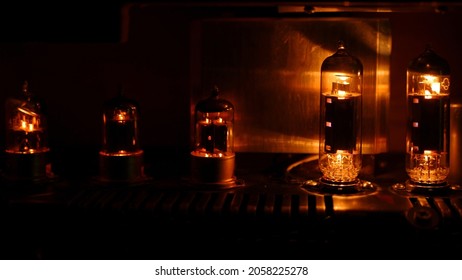 Close up silhouette of eletronic vacuum  radio tube. Old analog electronic audio components glowing orange. - Shutterstock ID 2058225278