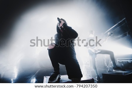 close up silhouette of rap & trap & hip hop star / singer perform on stage of nightclub. Dark background, smoke, concert  spotlights