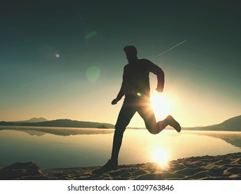 Close  silhouette of a runner man running along on the beach at sunset with sun in the background. Vintage effect style pictures.
