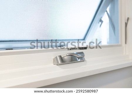 Close up of silver chrome window opening crank handle affixed to window sill with window open